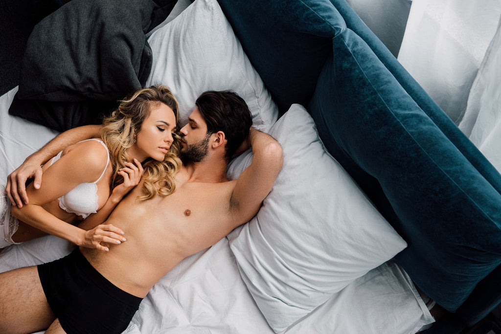Couple embracing in bed, discussing intimacy and sexual health.
